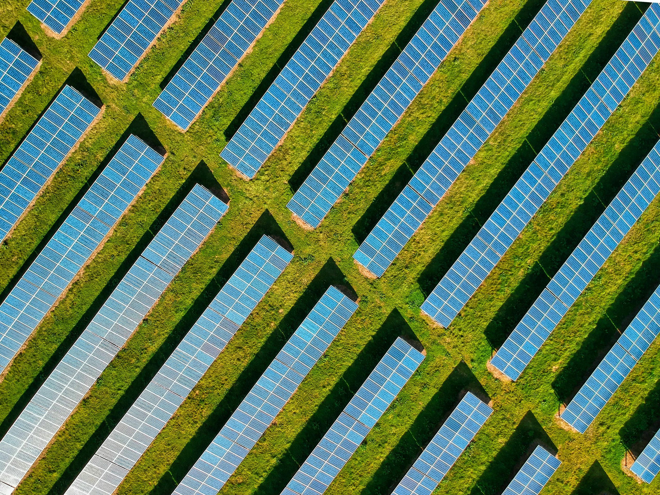 High-angle aerial shot of solar panels in a lush green field, located in Rockbeare, UK.